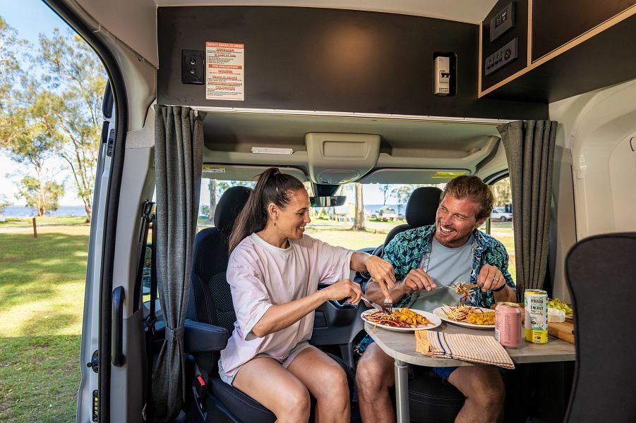 Man en vrouw zitten aan tafel voorin de Britz Voyager te eten