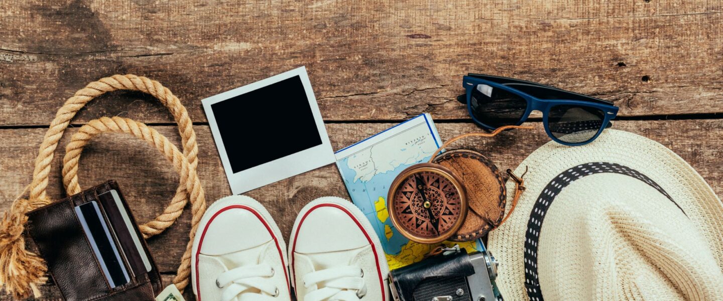Spullen die meegaan op reis liggen op de vloer: schoenen, zonnebril, hoed etc