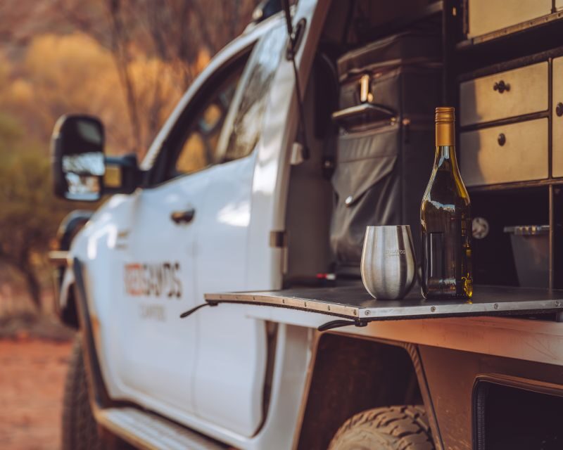 Aan de zijkant van de RedSands camper is de klep geopend waarachter onder andere de koelbox is en keukenbenodigdheden zijn opgeborgen in diverse laden