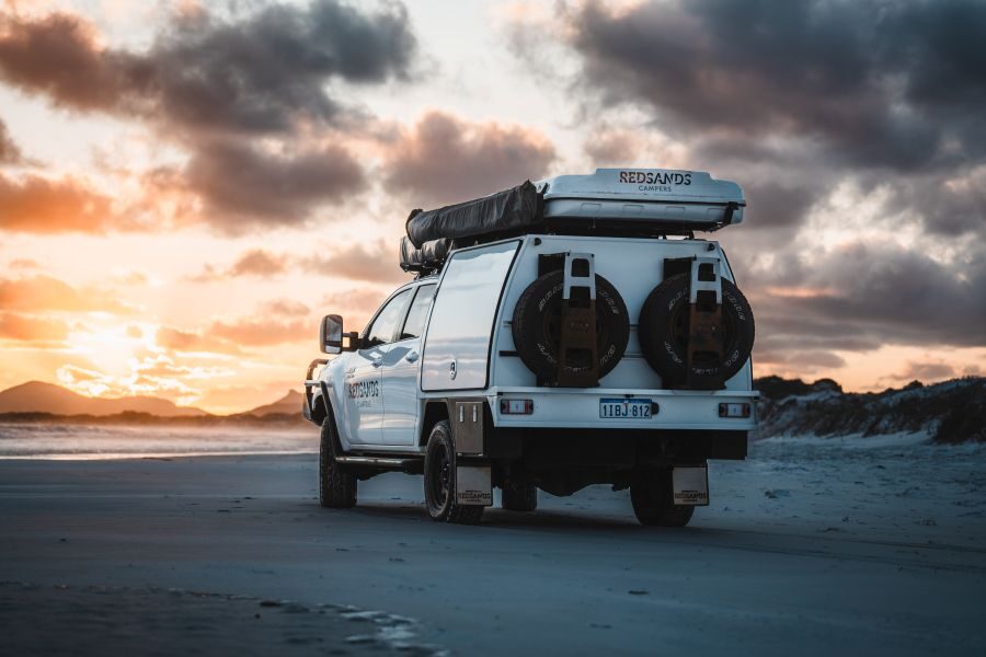 Genietend van het prachtige uitzicht bij zonsondergang bij Cape Le Grand - West Australië - met zicht op de achterzijde van de RedSands camper en reservewielen