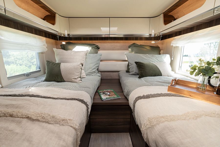 Twee opgemaakte eenpersoonsbedden met kastruimte erboven achterin de Britz Wanderer camper
