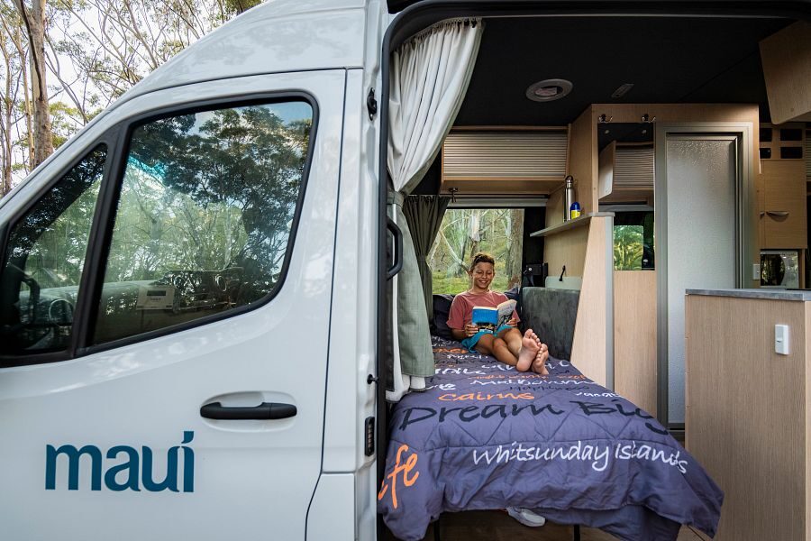 Een kind is een boek aan het lezen op het eenpersoonsbed voorin de Maui Ultima Plus camper