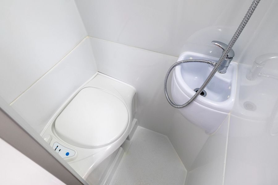 Het toilet en een wasbak in de badkamer van de Maui Ultima Plus camper