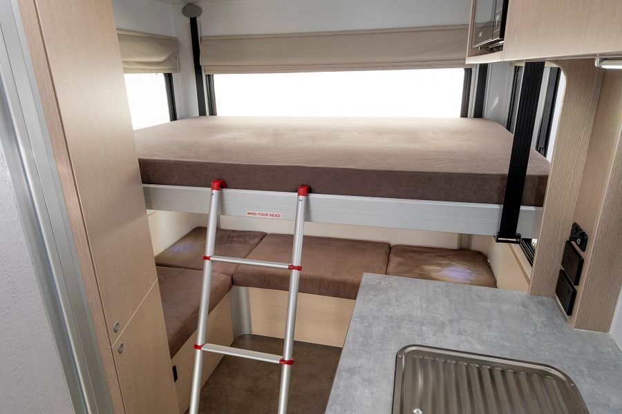 Het hefbed met vast matras en ladder boven de zithoek achterin de Maui Cascade camper