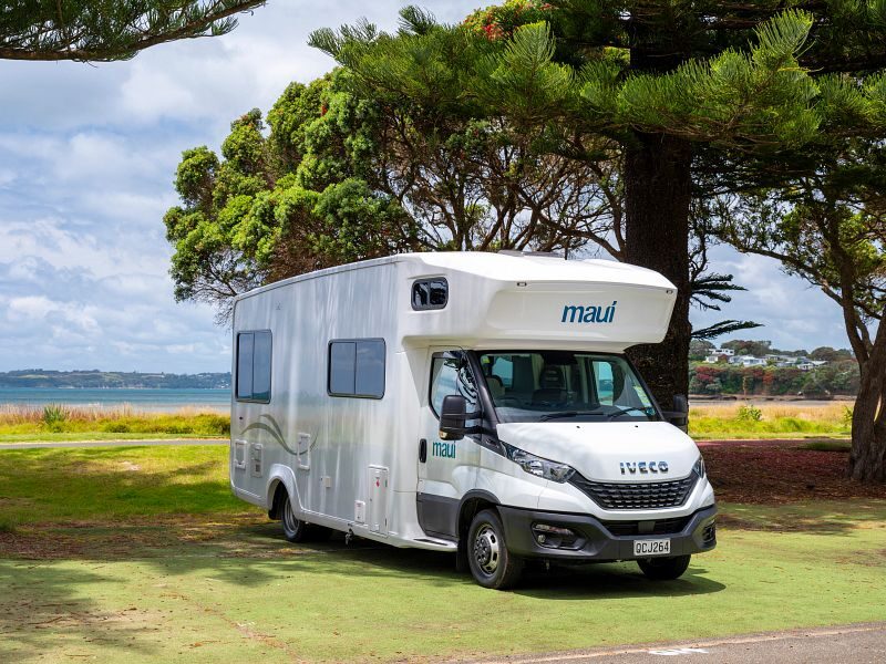 De voorkant van de Maui Beach camper die geparkeerd staat bij een boom op een grasveld