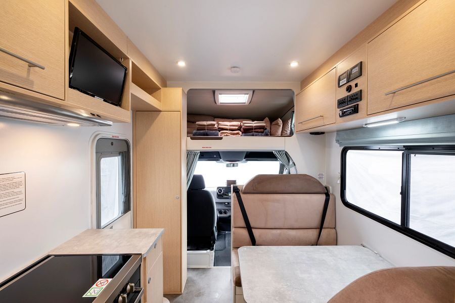 Het interieur van de Maui River camper van achter naar voor met de keuken, zitplaatsen in het midden en de bestuurdersruimte met de alkoof erboven