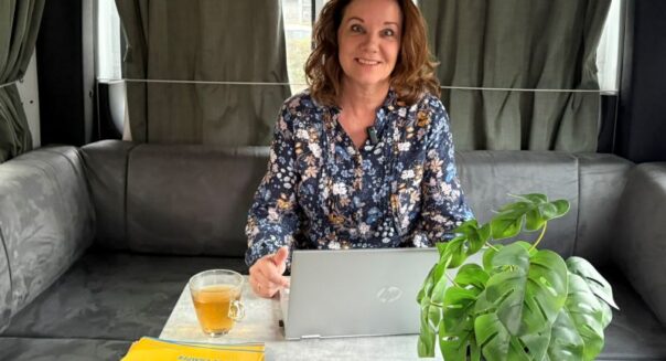 Karin Kramer zit in de camper met kop thee en laptop