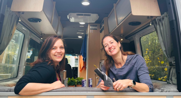 Carolien en Leonore van het administratie team van Campers Down Under zitten in de camper met de achterdeur open