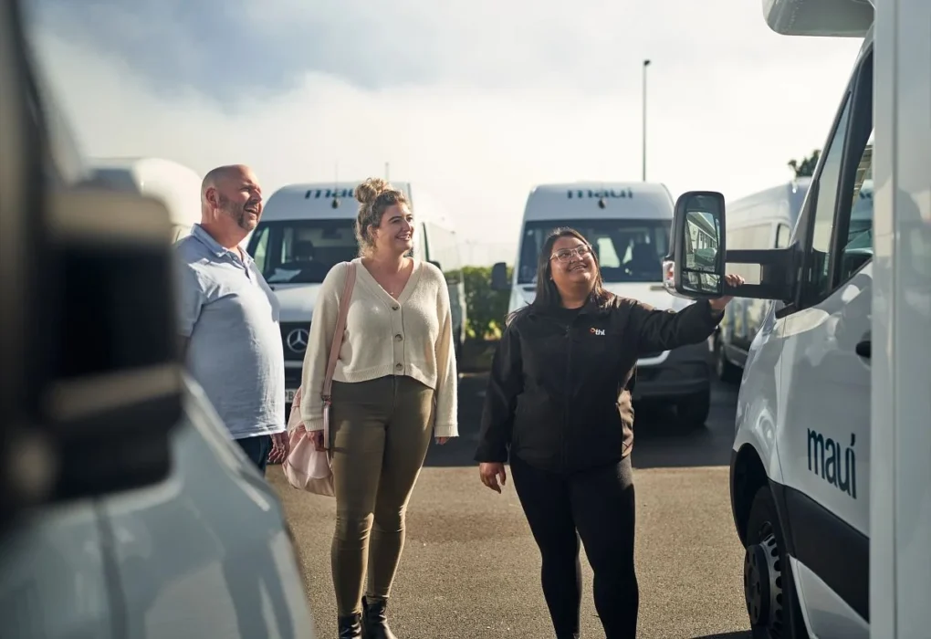 Man en vrouw halen camper op in Nieuw-Zeeland en krijgen uitleg van een medewerker