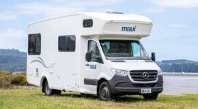 De Maui Sunset camper vanaf de voor- en zijkant geparkeerd langs het water op het gras in Australië