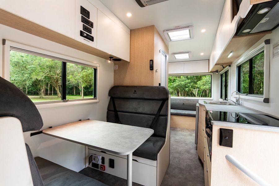 Het interieur van voor naar achter van de Maui Sunset camper met twee zithoeken, keuken en veel ramen