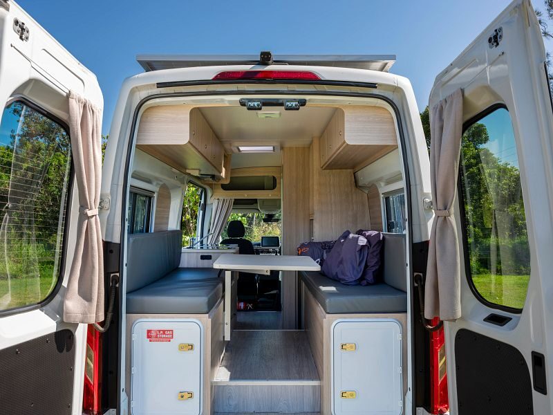 De achterkant van de Apollo Hitop camper in Australië met de achterdeuren open waar de zithoek is die je kunt ombouwen tot tweepersoonsbed