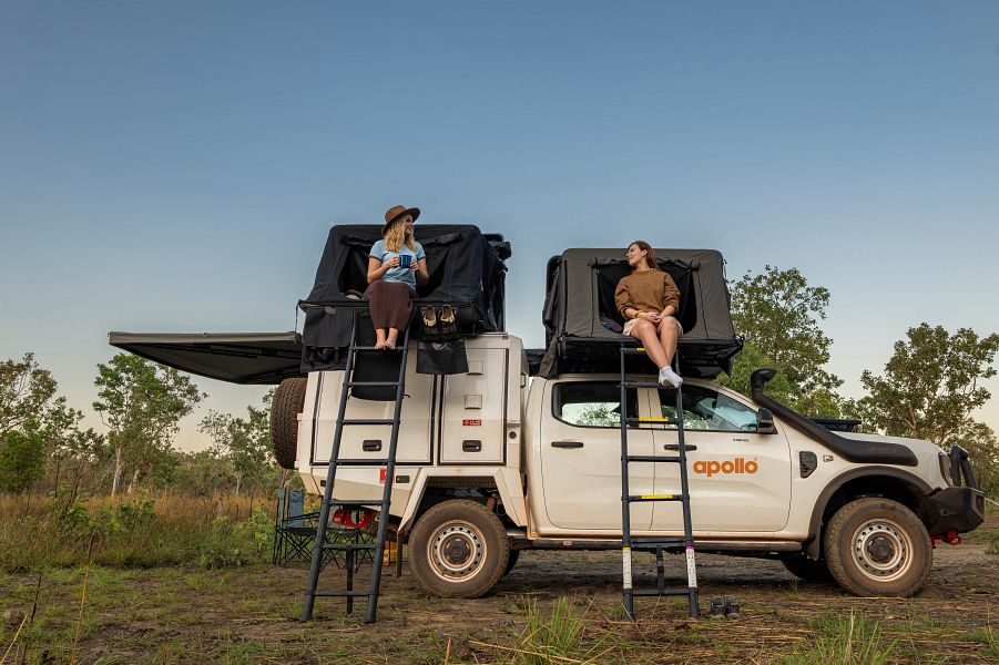 Twee vrouwen zitten in de opening van de twee daktenten van de Apollo 4WD Overland Camper die geparkeerd staat in Australië