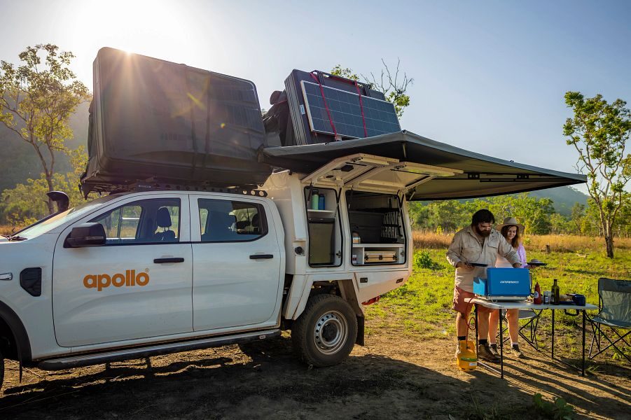 Een koppel staat aan de zijkant van de Apollo 4WD Overland Camper te koken op de buitenkeuken onder de luifel in Australië