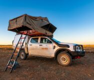 De zijkant van de Apollo 4WD Overland Camper met de daktenten en ladder uitgeklapt in Australië