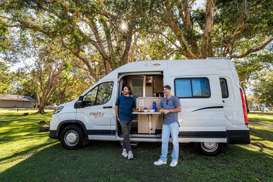 Twee mannen staan aan de uitklapbare buitentafel aan de zijkant van de Mighty Duo camper in Australië