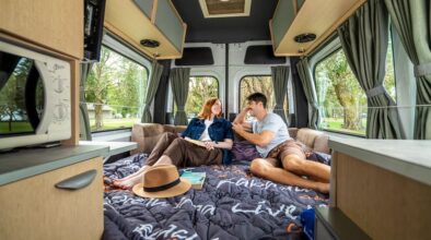 Een koppel kijkt naar elkaar zittend op het tweepersoonsbed in de Mighty Deuce Plus camper