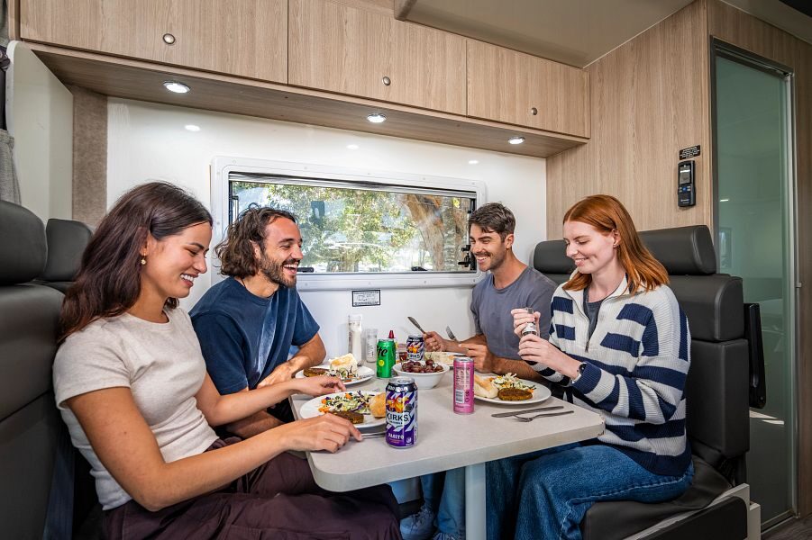 Vier vrienden zitten aan tafel in de zithoek in het midden van de Mighty Double Up te eten