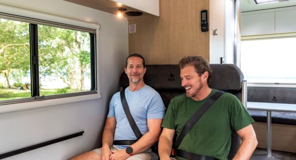 Twee mannen zitten in de gordels in de bank in de dinette van de camper
