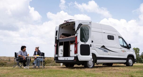 Een stel zit aan de achterkant van de Mighty Lite HiLITE camper op de campingstoelen in de natuur van Nieuw-Zeeland