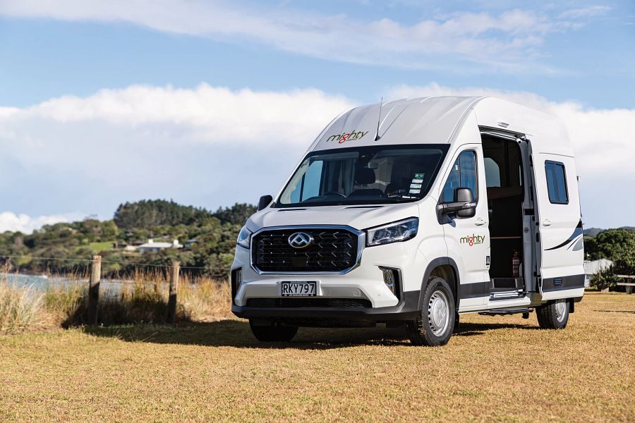 De Mighty Lite HiLITE camper staat geparkeerd op een grasveld in Nieuw-Zeeland met de zijdeur open