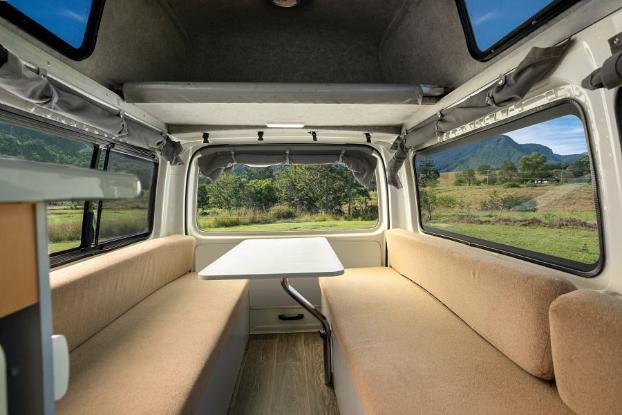 De zitbanken met tafel achterin de Mighty Lite HiLITE camper in Australië