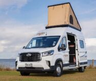 De Mighty Lite DeLITE camper staat geparkeerd op een grasveld met de daktent uitgeklapt en de zijdeur open in Nieuw-Zeeland