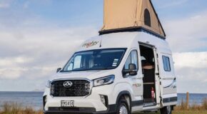 De Mighty Lite DeLITE camper staat geparkeerd op een grasveld met de daktent uitgeklapt en de zijdeur open in Nieuw-Zeeland