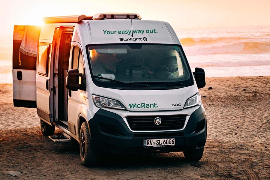 De voorkant van de McRent Urban Plus camper die geparkeerd staat op het strand