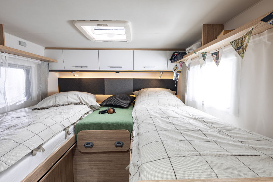 De twee eenpersoonsbedden met kastruimte boven de bedden achterin de McRent Family Standard camper