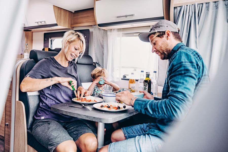 Een gezin zit aan tafel te eten in de McRent Family Standard camper