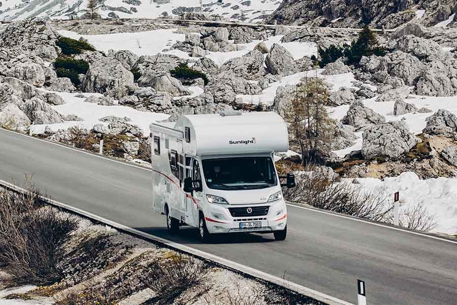 De McRent Family Plus camper rijdt op een geasfalteerde weg door de besneeuwde omgeving