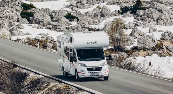 De McRent Family Plus camper rijdt op een geasfalteerde weg door de besneeuwde omgeving