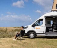 Man zit in campingstoel naast Britz Voyager op het Noordereiland