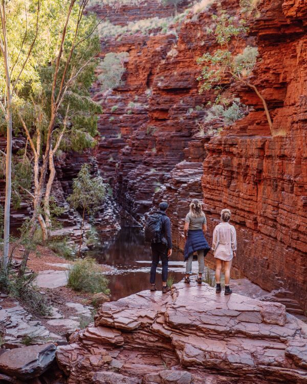 Drie mensen staan te kijken in een kloof in Karijini National Park