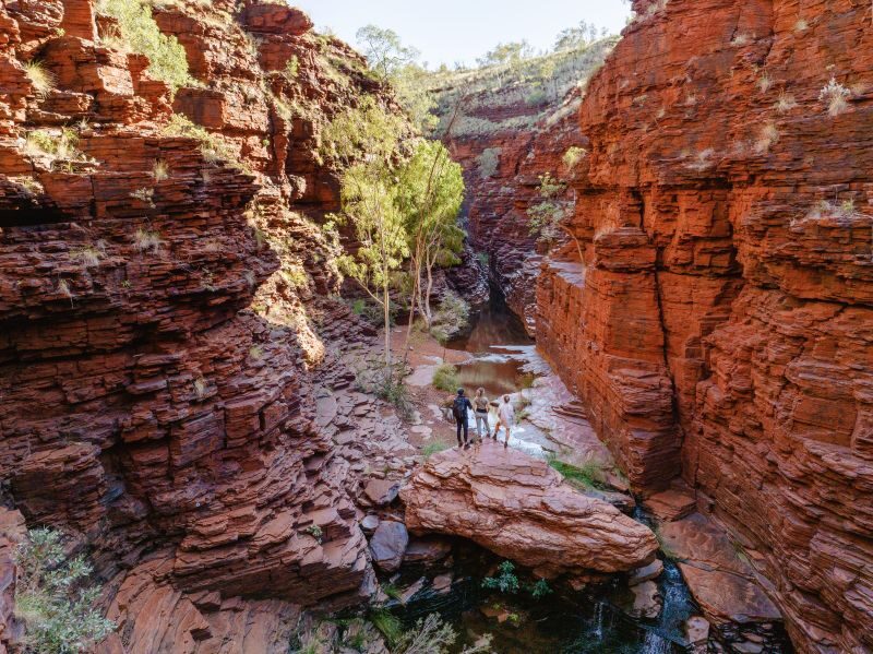 Drie mensen staan te kijken in een kloof in Karijini