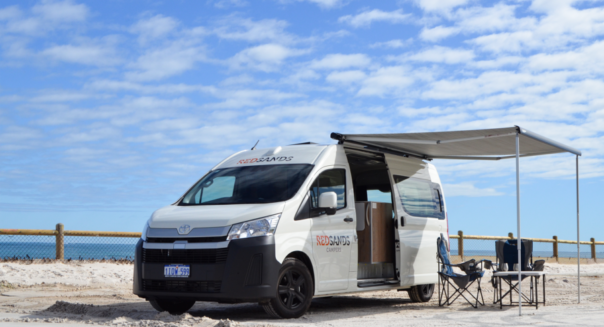 De RedSands camper op het strand met de zijdeur geopend en de campingtafel en stoelen onder de uitgeklapte luifel