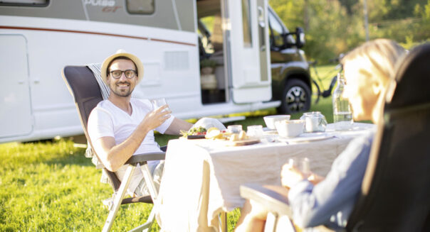 Een man zit tegenover zijn vrouw op een campingstoel aan de zijkant van de McRent Comfort Plus