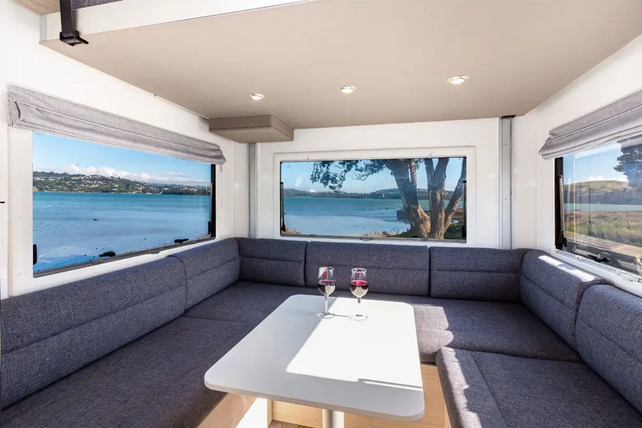 De ruime zithoek met tafel en grote ramen achterin de Pacific Horizon Gem 4 camper