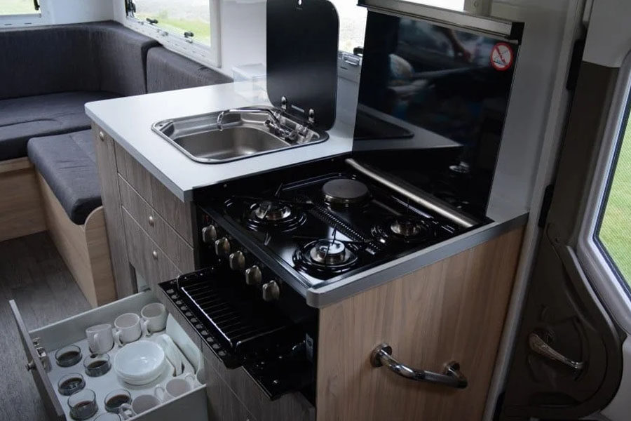 De keuken met gasfornuis, wasbak en open ladekast voor keukengerei in de Pacific Horizon Sam 6 camper Nieuw-Zeeland