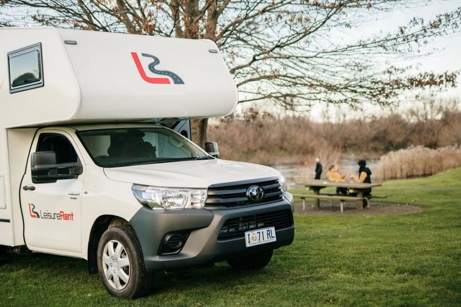 Voorgedeelte van de Leisure Rent 4 Berth Motorhome, mensen in de achtergrond aan een picknicktafel