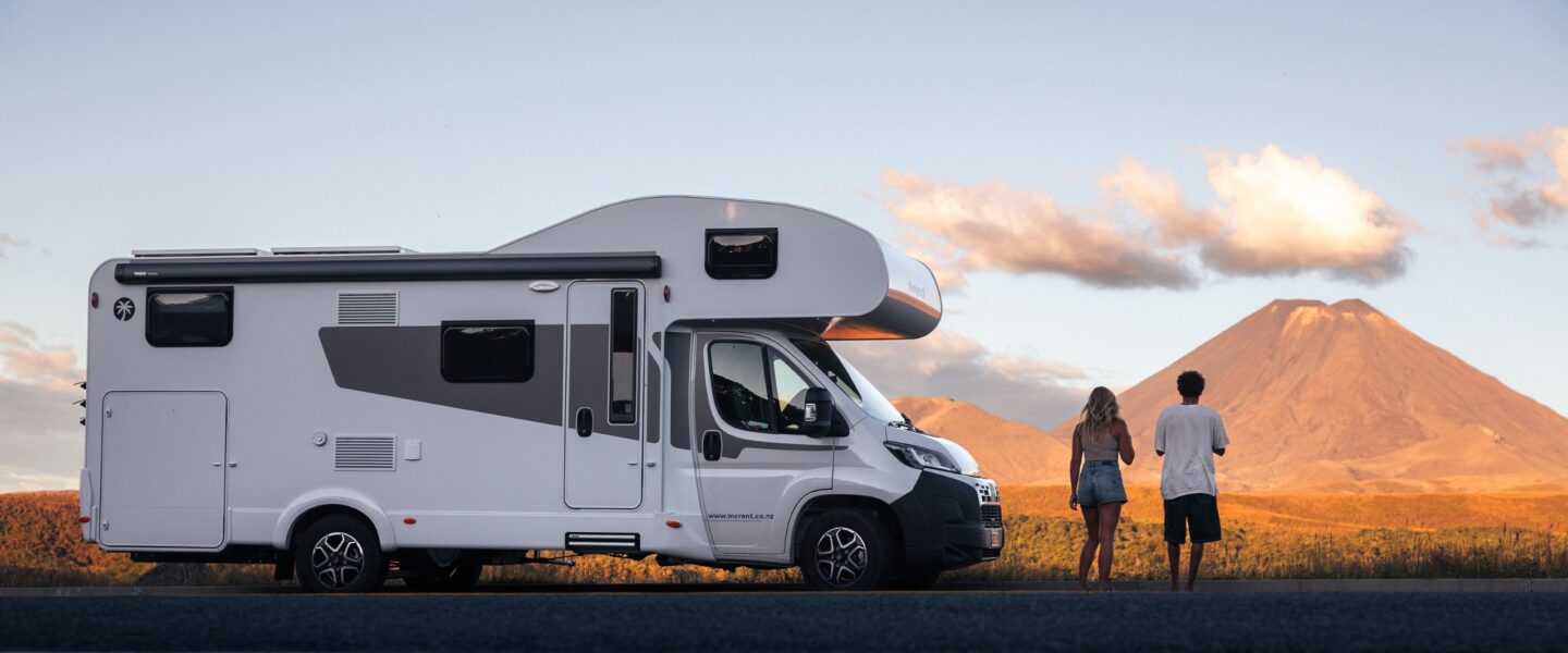 Stel staat naast geparkeerde McRent camper naar zonsondergang te kijken