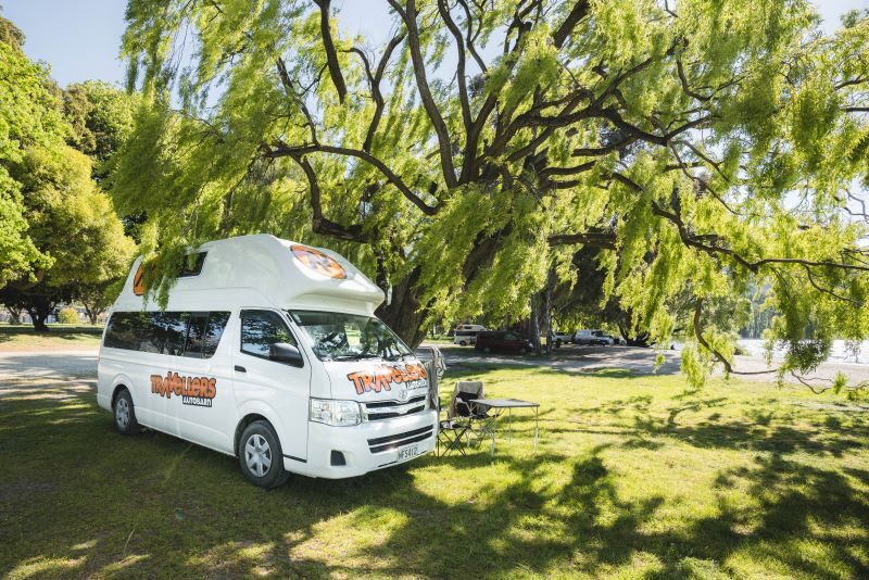 Travellers Autobarn Hi5 staat onder een boom op een camping