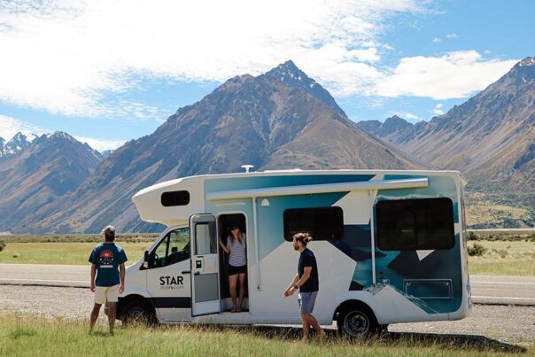 Een vrouw staat in de deuropening van de Star RV Polaris 6 camper en kijkt naar haar vrienden die genieten van het uitzicht