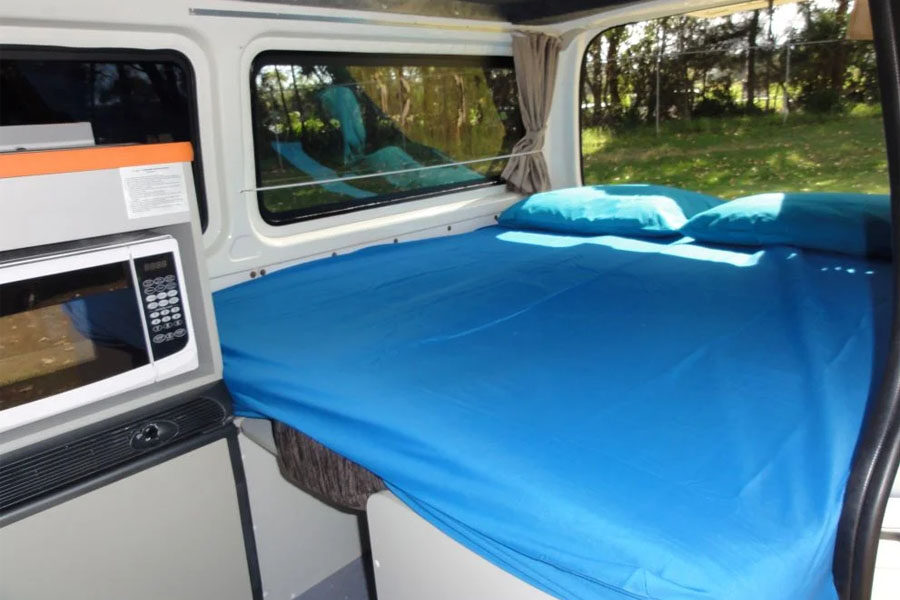 Het opgemaakte tweepersoonsbed achterin de Travellers Autobarn Kuga camper