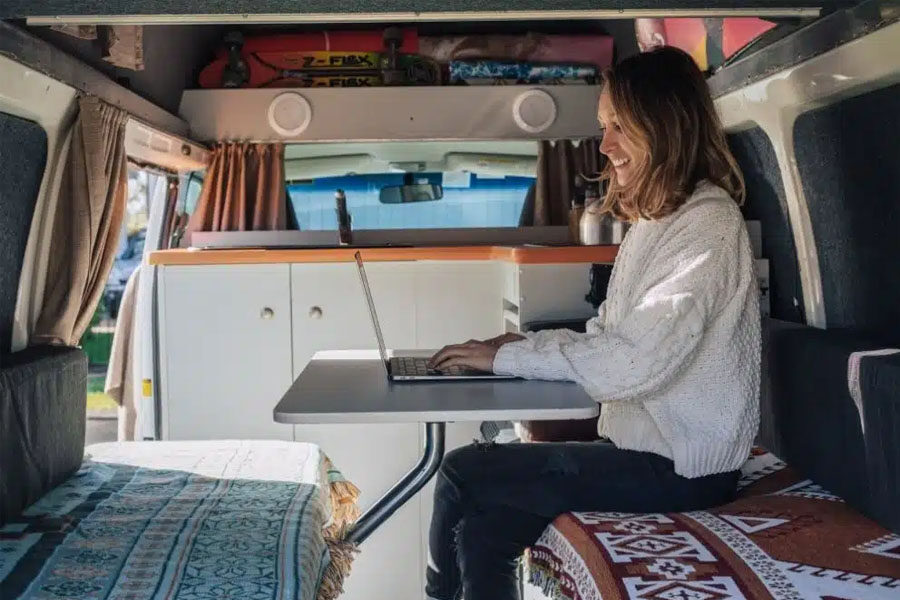 Een vrouw zit met haar laptop in de zithoek achterin de Travellers Autobarn Kuga camper