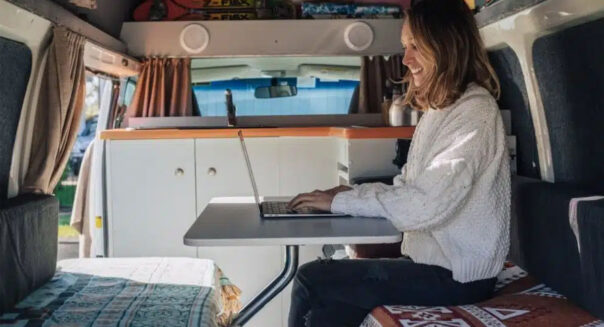 Een vrouw zit met haar laptop in de zithoek achterin de Travellers Autobarn Kuga camper