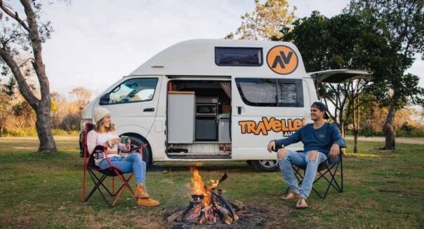Een stel zit op de campingstoelen bij een kampvuur voor de Travellers Autobarn Kuga camper