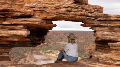 Vrouw zit in het gat van Natures Window uit te kijken over de Murchison River in Kalbarri National Park