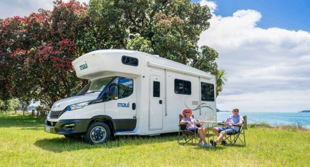 Een koppel zit voor de Maui Beach camper in de omgeving van Auckland